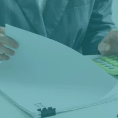 Profesional revisando documentos en papel y usando una calculadora, símbolo del cálculo manual de la huella de carbono antes del Real Decreto 214/2025