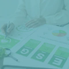 Persona analizando informes de huella de carbono e indicadores ESG sobre una mesa de trabajo, con el logo de Presgo superpuesto.