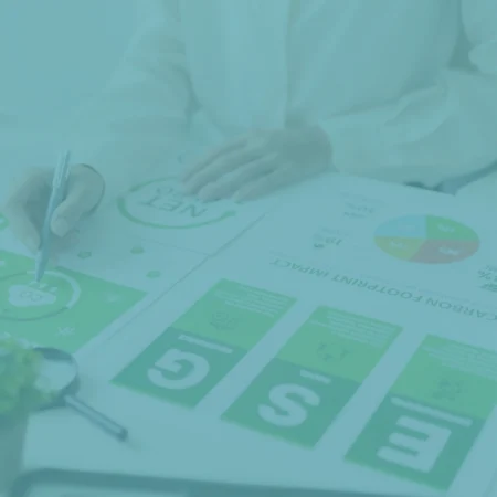 Persona analizando informes de huella de carbono e indicadores ESG sobre una mesa de trabajo, con el logo de Presgo superpuesto.