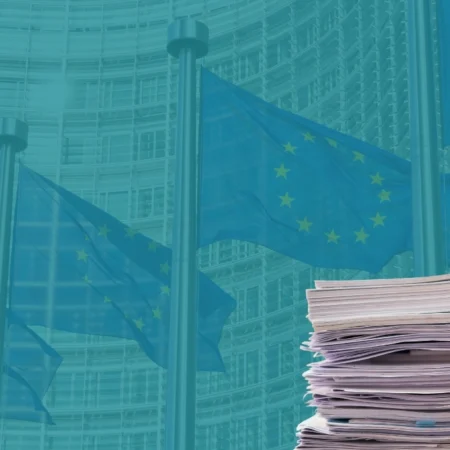 Banderas de la UE ante la sede de la Comisión Europea y una pila de documentos que ilustra el ómnibus CSRD